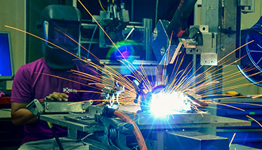 Vergrößerungsansichten für Bild: Beschäftigter mit Schutzvisier beim Betrieb einer Laserschweißmaschine.