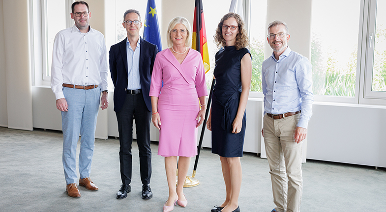 Das Foto zeigt Prof. Dr. phil. habil. Thomas Müller, Prof. Dr. Markus Paulus, Sozialministerin Ulrike Scharf, Prof. Dr. Birgit Prodinger und Prof. Dr. med. Steffen Berweck